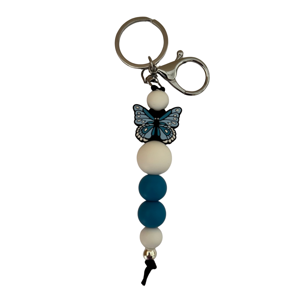 An 18cm keyring featuring a blue butterfly silicone bead and white and blue round silicone beads.