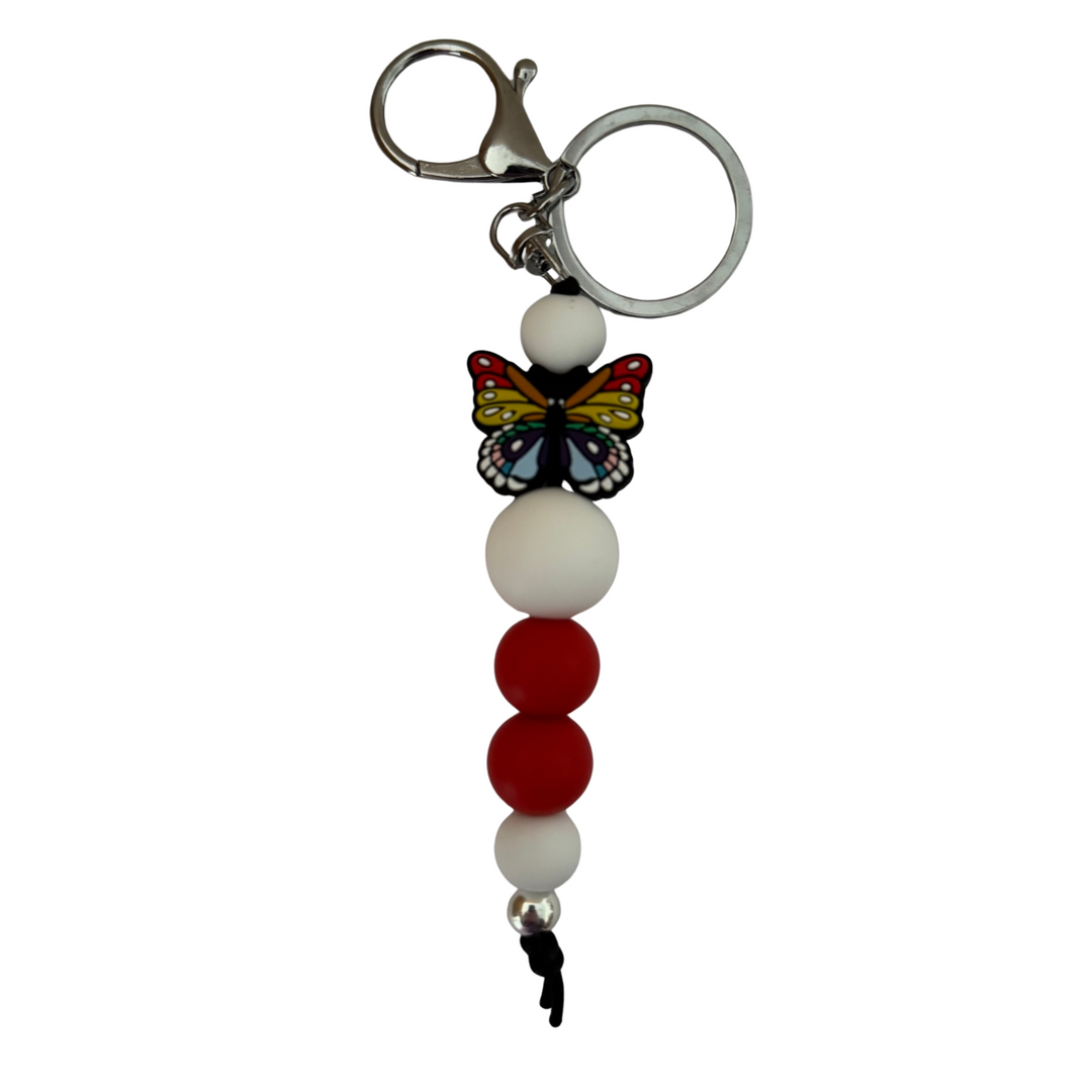 An 18cm keyring featuring a multi coloured butterfly silicone bead and white and red round silicone beads.