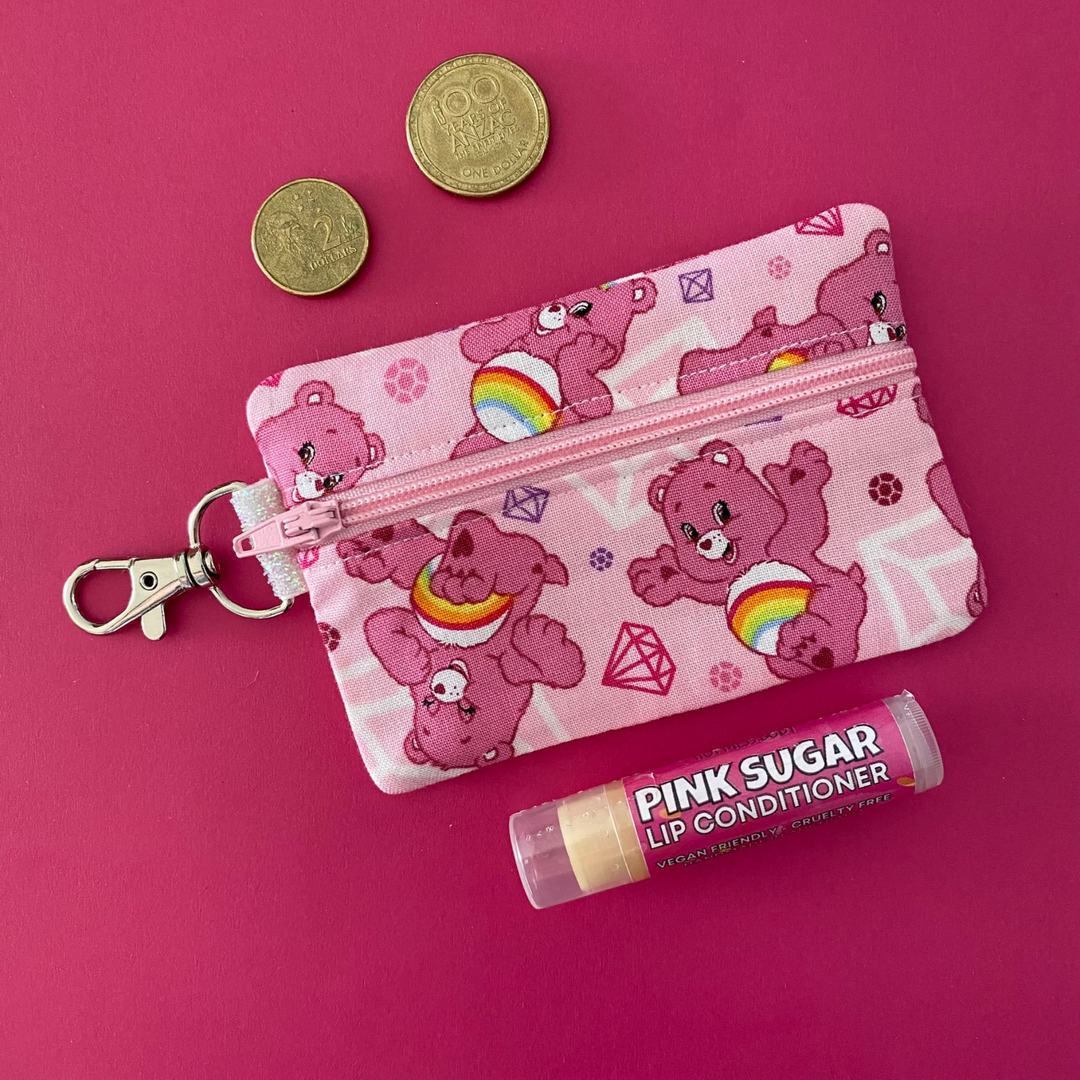 A small clip coin purse perfect for coins and small essentials featuring a pink Care Bear on pink fabric.
