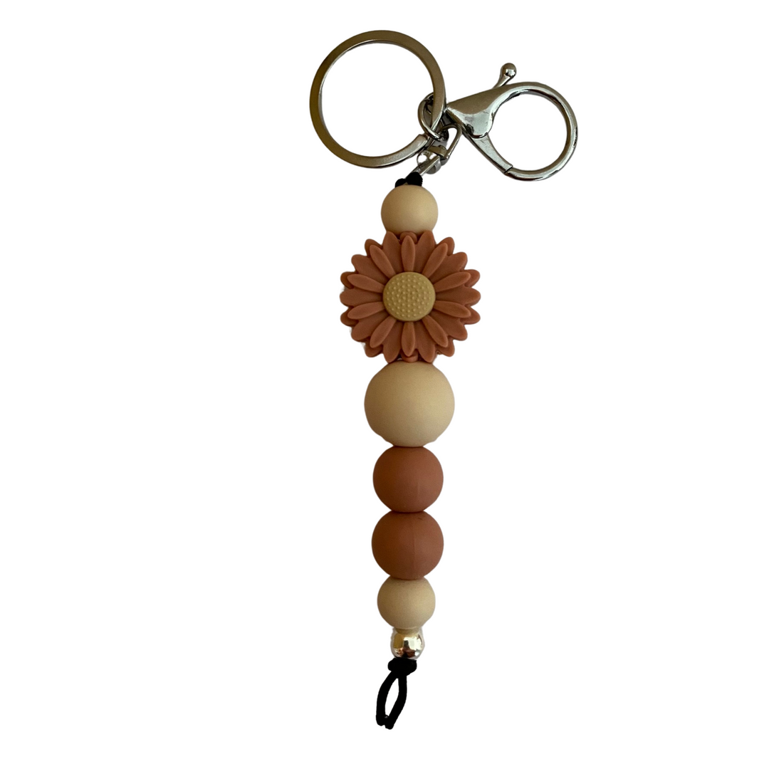 An 18cm keyring with a clay coloured daisy silcone beads and other assorted beads.