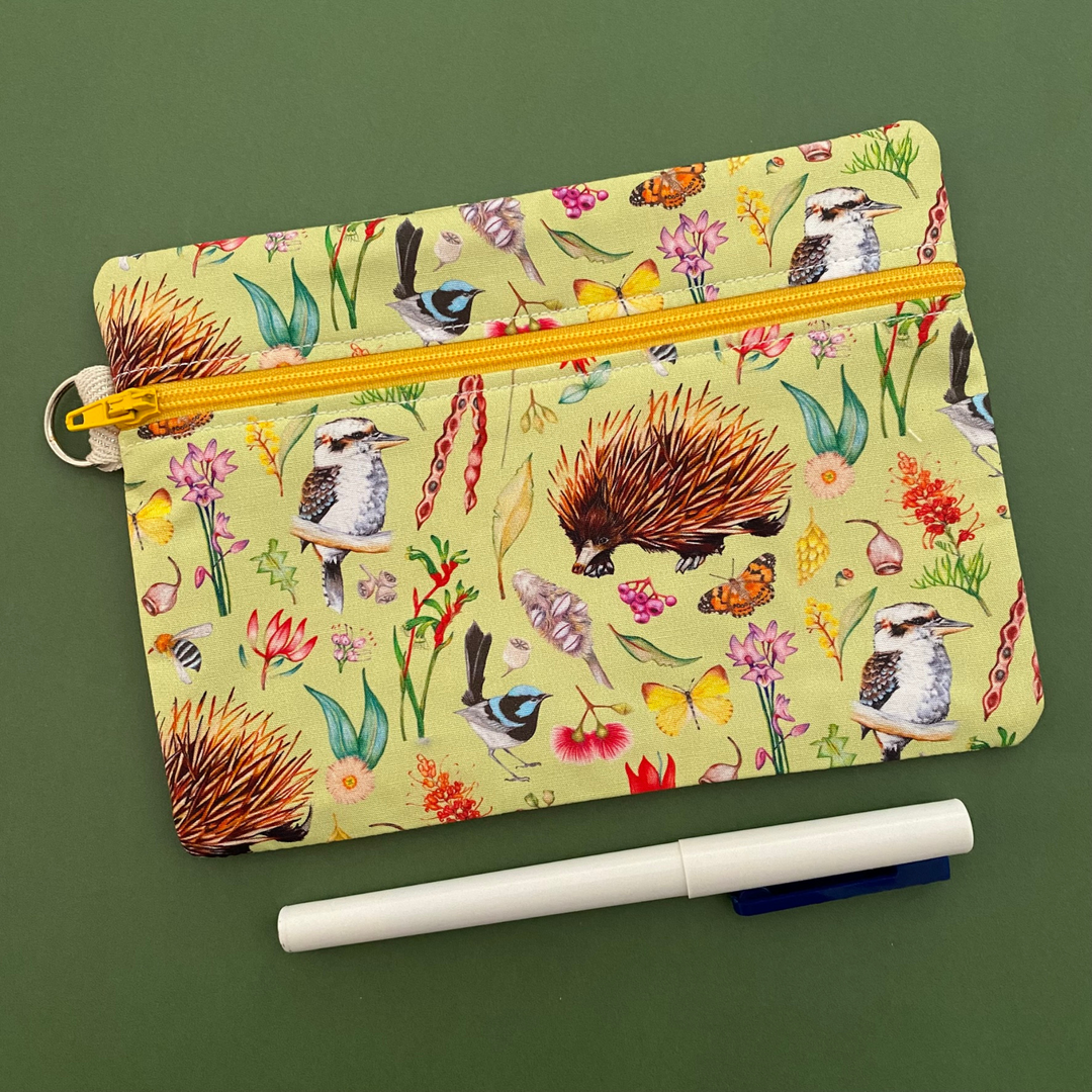 Featuring charming illustrations by Wollongong artist My Tiny Explorer, this design celebrates iconic Australian animals like the Echidna, Kookaburra, Blue-banded Bee, and Superb Fairy-wren, surrounded by stunning native flora.