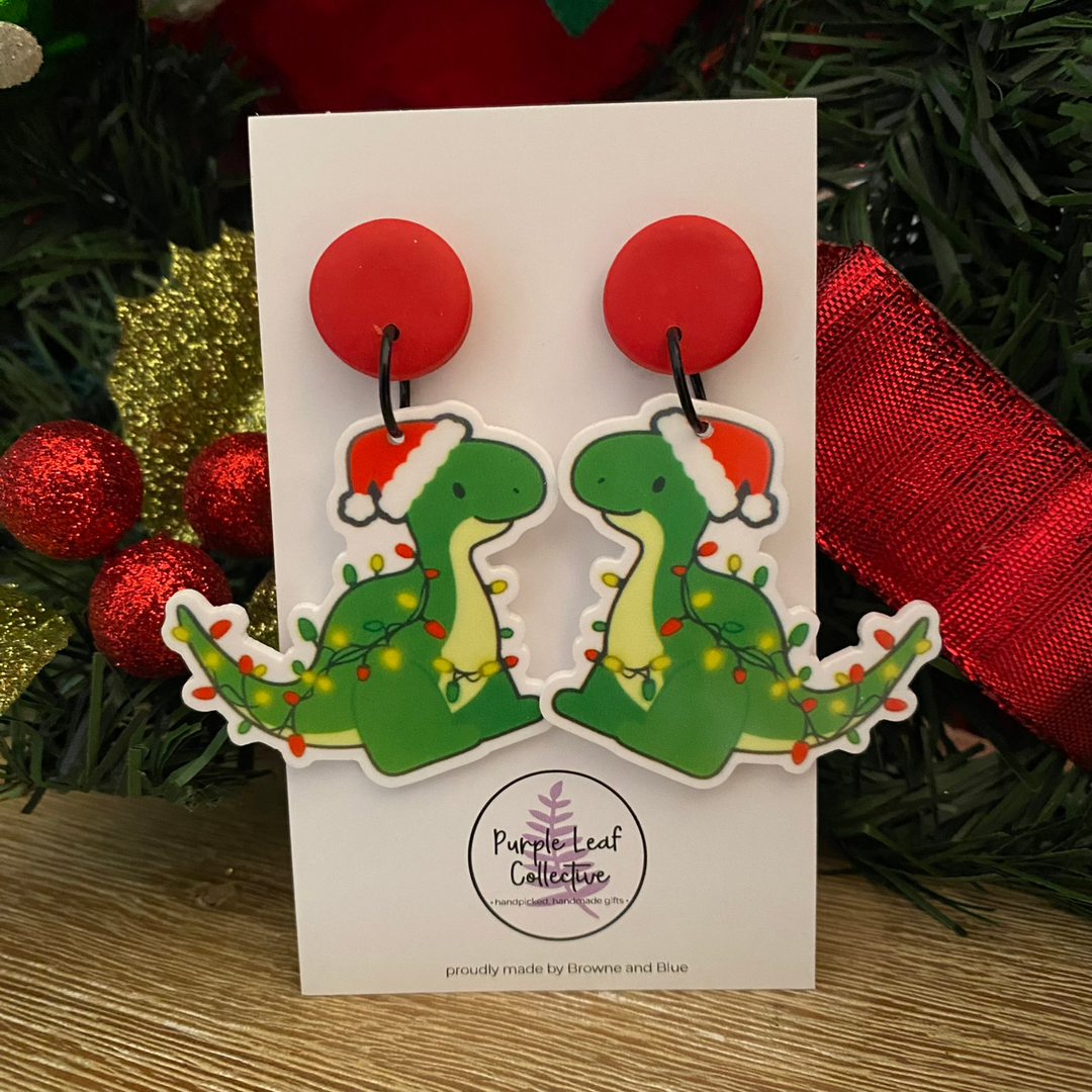 A pair of green dinosaurs wearing festive lights with red stud topper on a white card.