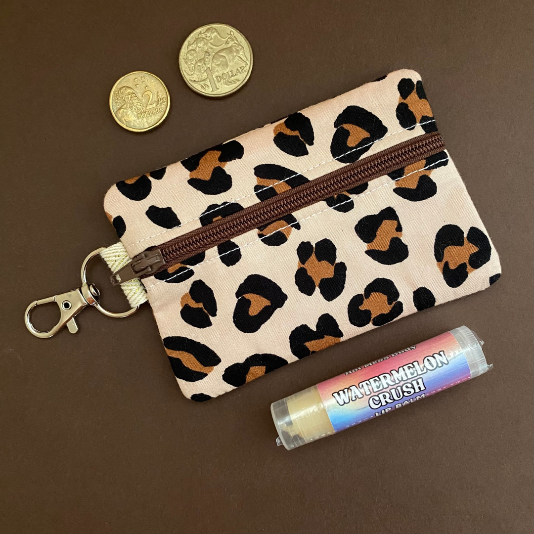 A clip coin purse with images of brown leopard prints on brown fabric.