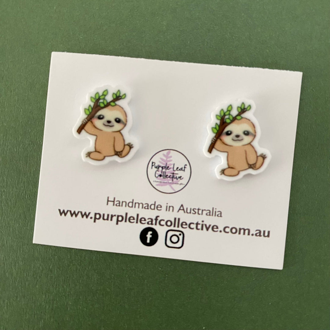 Sloth holding a tree branch novelty stud earrings. Hypoallergic Surgical Steel Posts. Printed Acrylic. Approx 15mm.