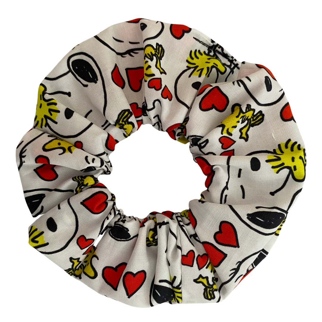 Our Snoopy Love Scrunchies featuring sweet red love hearts alongside playful illustrations of Snoopy and Woodstock on a white fabric.