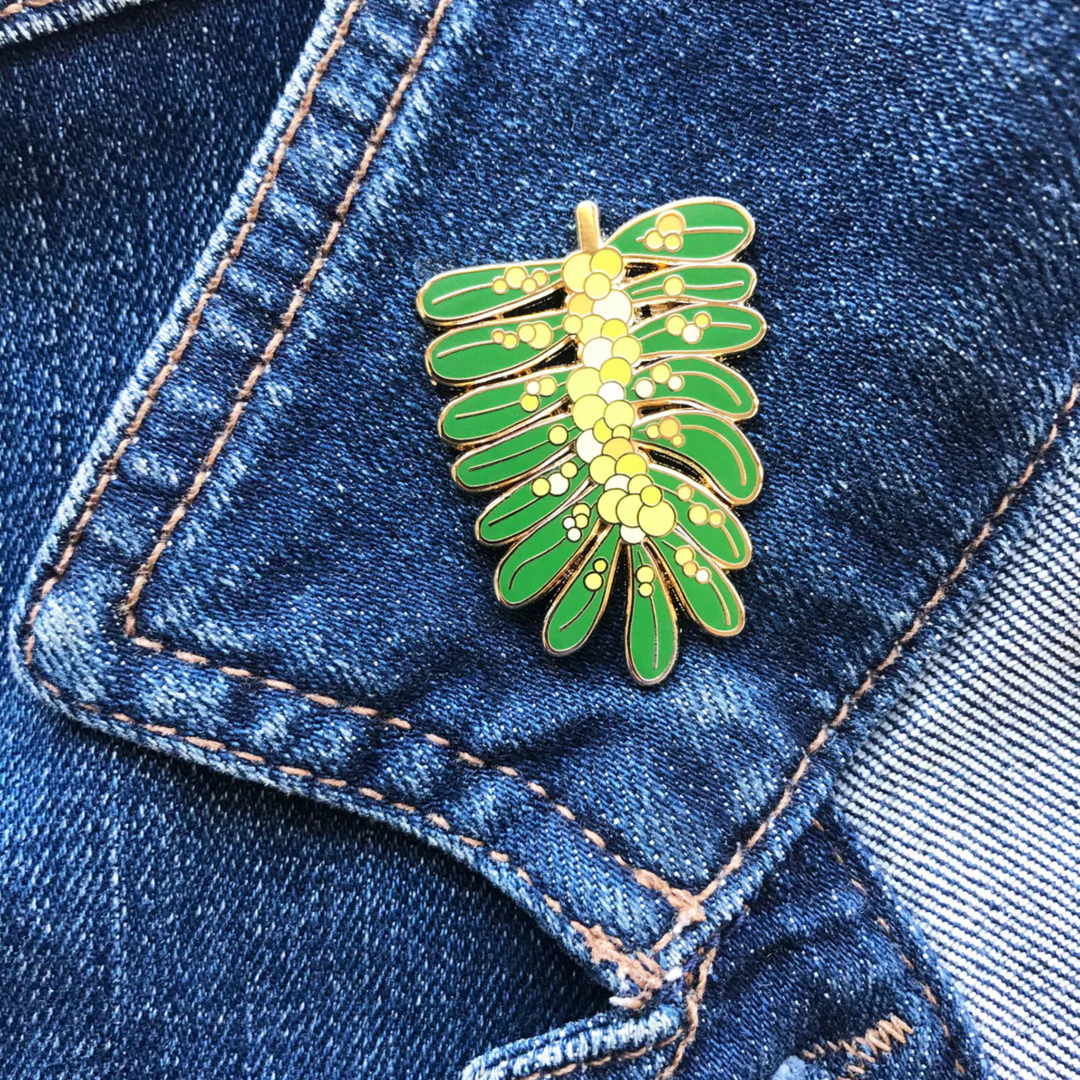A picture of the Acacia Enamel Pin pinned to a denim jacket.
