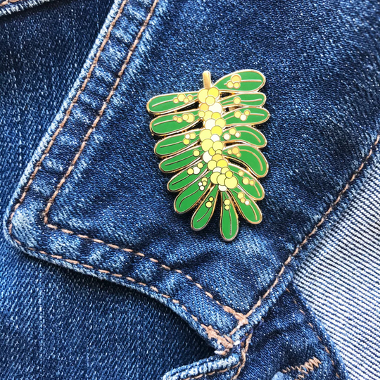 A picture of the Acacia Enamel Pin pinned to a denim jacket.