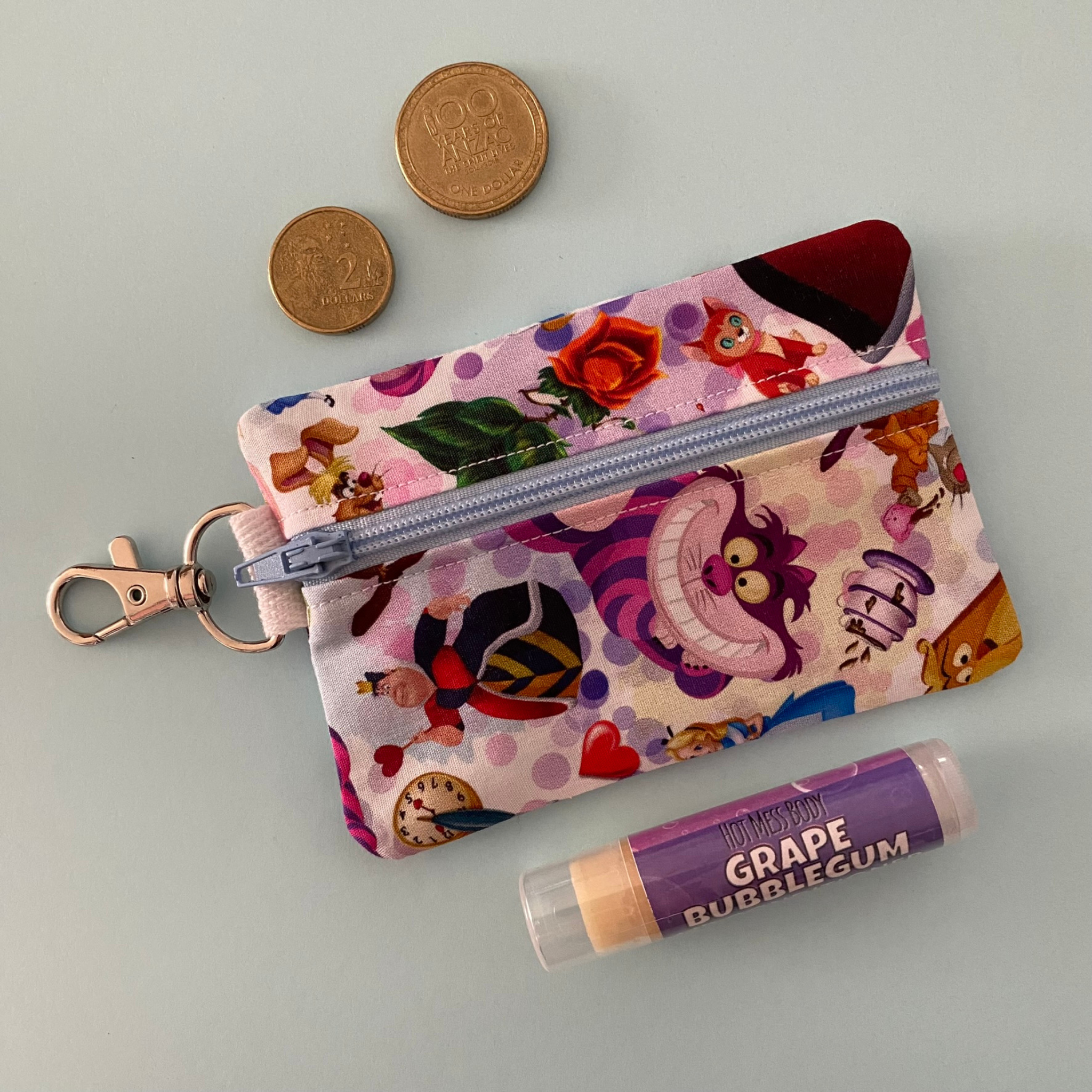 A small clip coin purse perfect for coins and small essentials featuring Alice in Wonderland characters fabric.