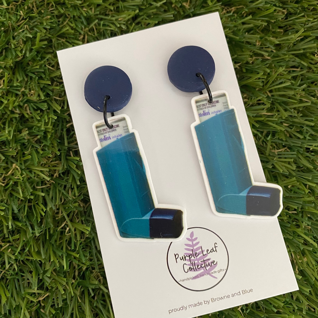 A pair of dangle earrings featuring two puffers set on navy blue clay tops.