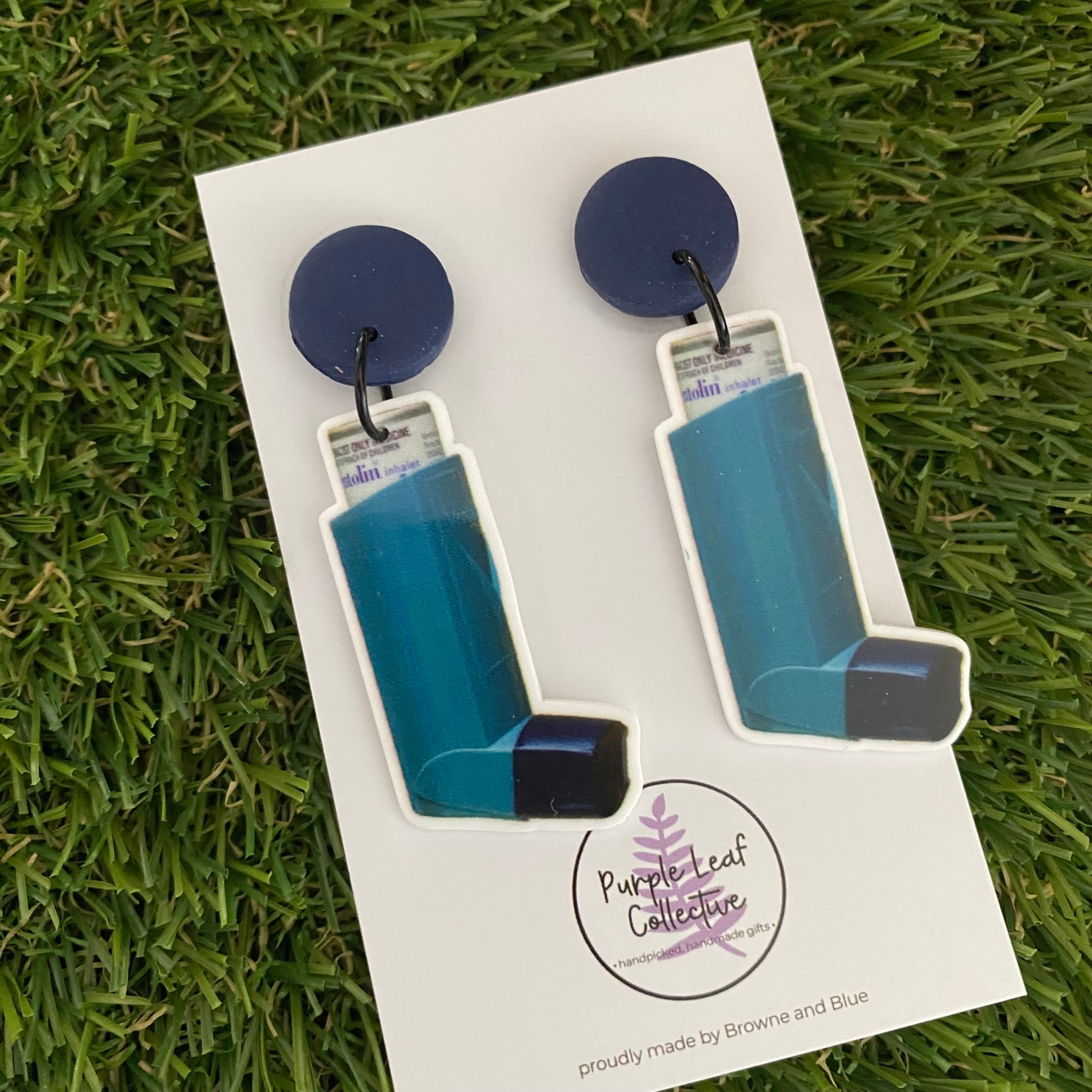 A pair of dangle earrings featuring two puffers set on navy blue clay tops.