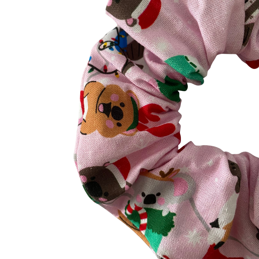 Close up view of multicoloured scrunchie with Aussie animals design on a pink fabric.