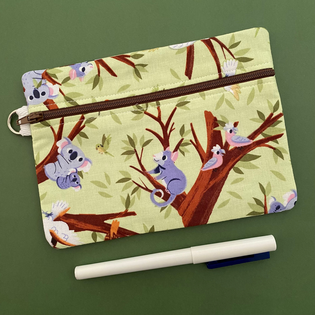 A medium zipper pouch featuring  images of Koalas, Cockatoos, Galahs, Ringtail Possums, Kookaburras, and Rainbow Lorikeets. 