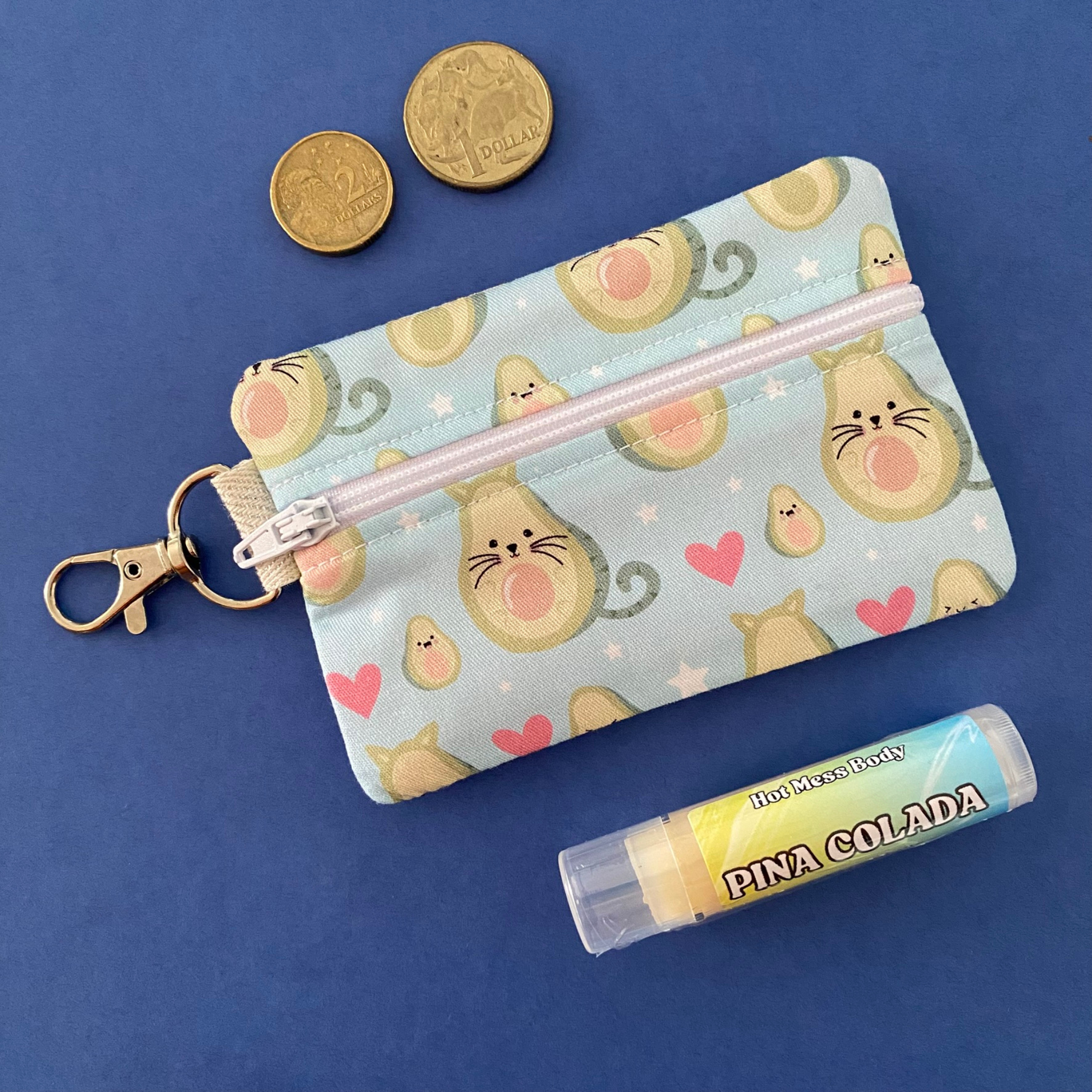 A clip coin purse with images of cats in avocados on a light blue fabric.