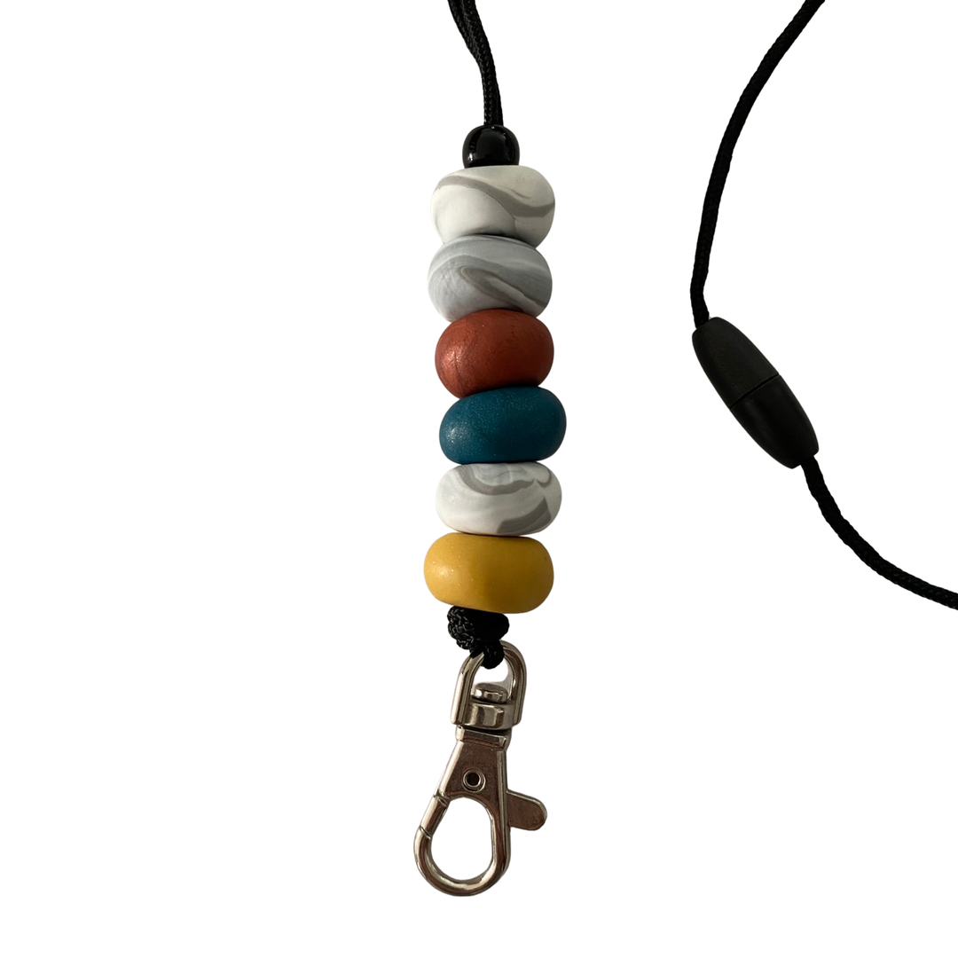 Polymer clay lanyard with six hand-rolled beads in brown, mustard, teal and marbled effects. Threaded on a nylon cord with a breakaway safety clasp and a silver-plated clip.