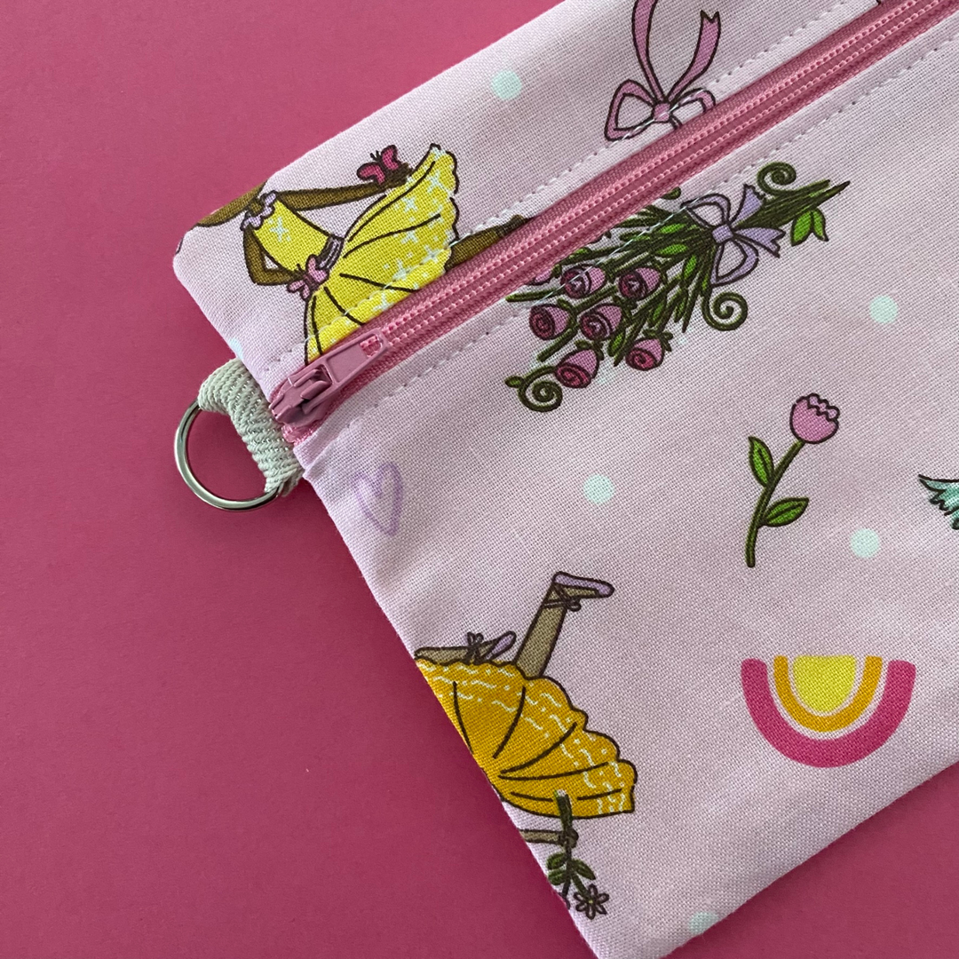 Clasp view of Ballet Girls zipper pouch, featuring endearing designs of ballerinas beautifully adorned with bouquets, flowers and hearts on a pink fabric.