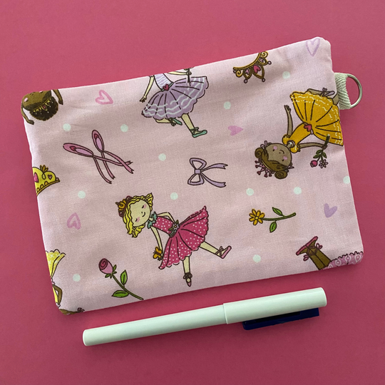 Reverse view of Ballet Girls zipper pouch, featuring endearing designs of ballerinas beautifully adorned with bouquets, flowers and hearts on a pink fabric.