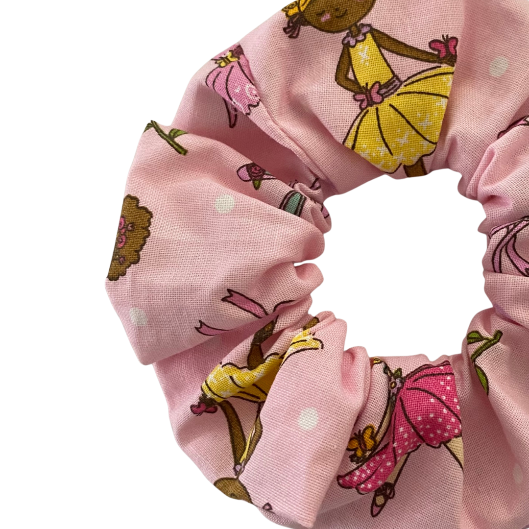 Close up view of a pink scrunchie with ballerinas beautifully adorned with bouquets, flowers and hearts.