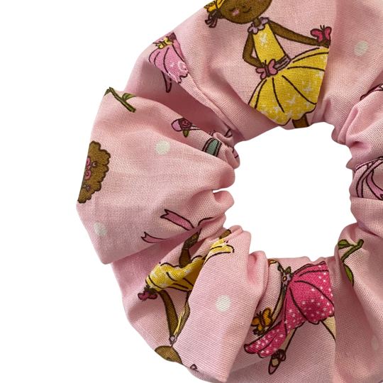 Close up view of a pink scrunchie with ballerinas beautifully adorned with bouquets, flowers and hearts.