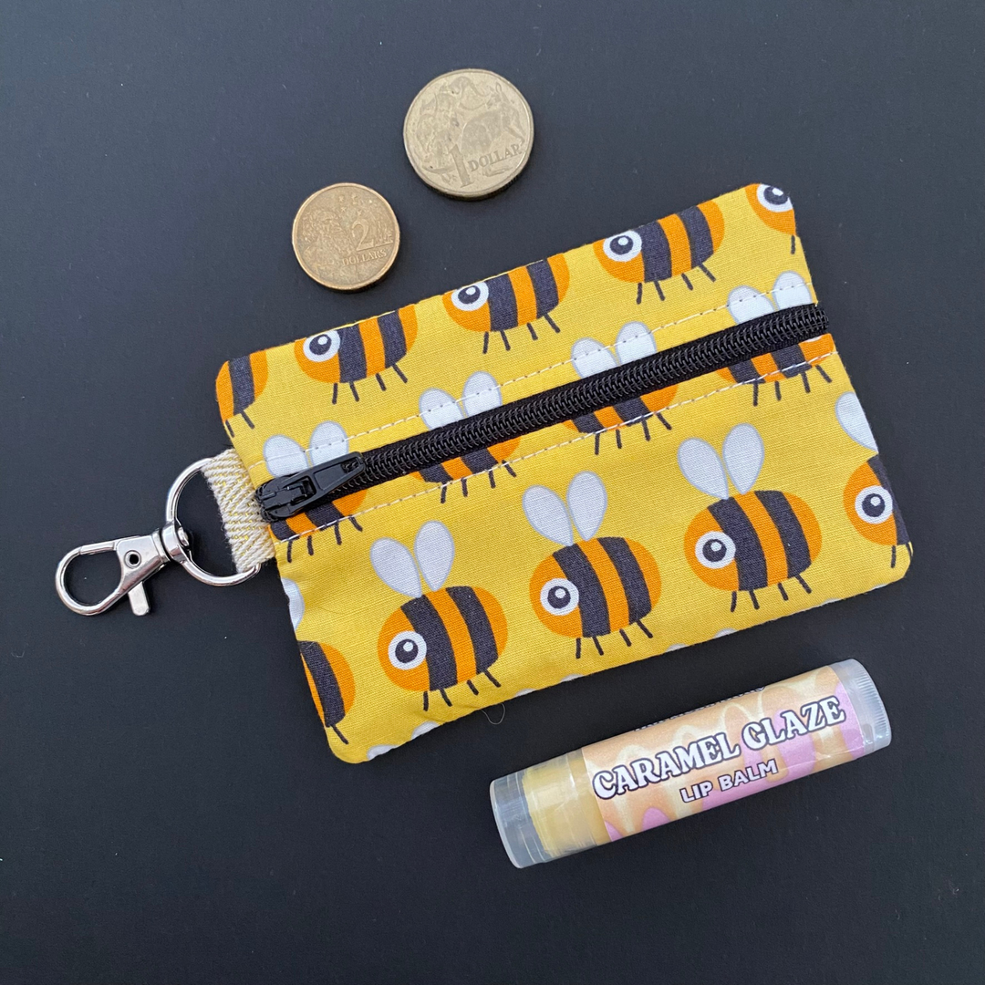 A small clip coin purse perfect for coins and small essentials with sweet bee-themed details on a yellow fabric.