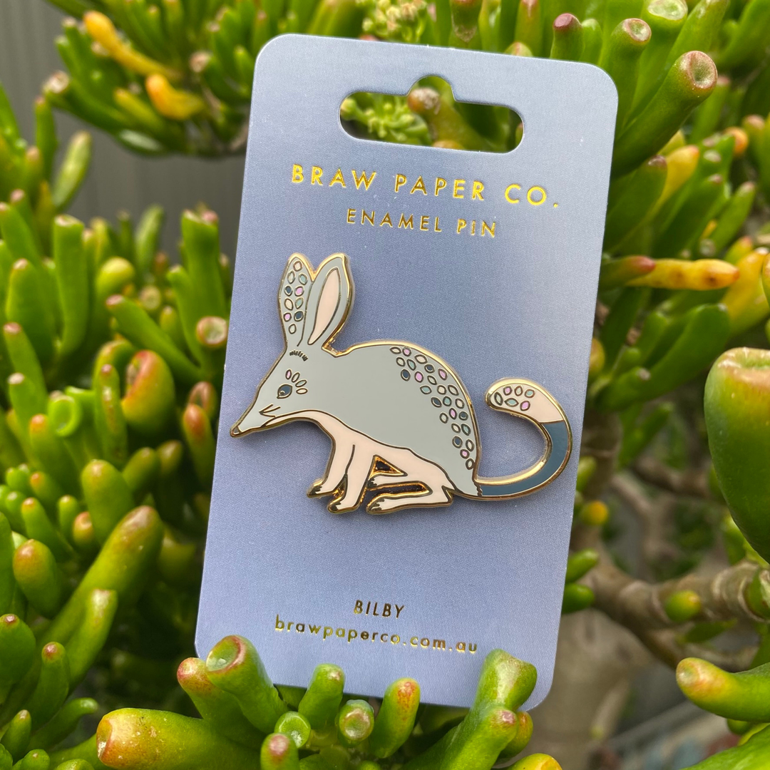 A picture of a Bilby enamel pin on a backing card.