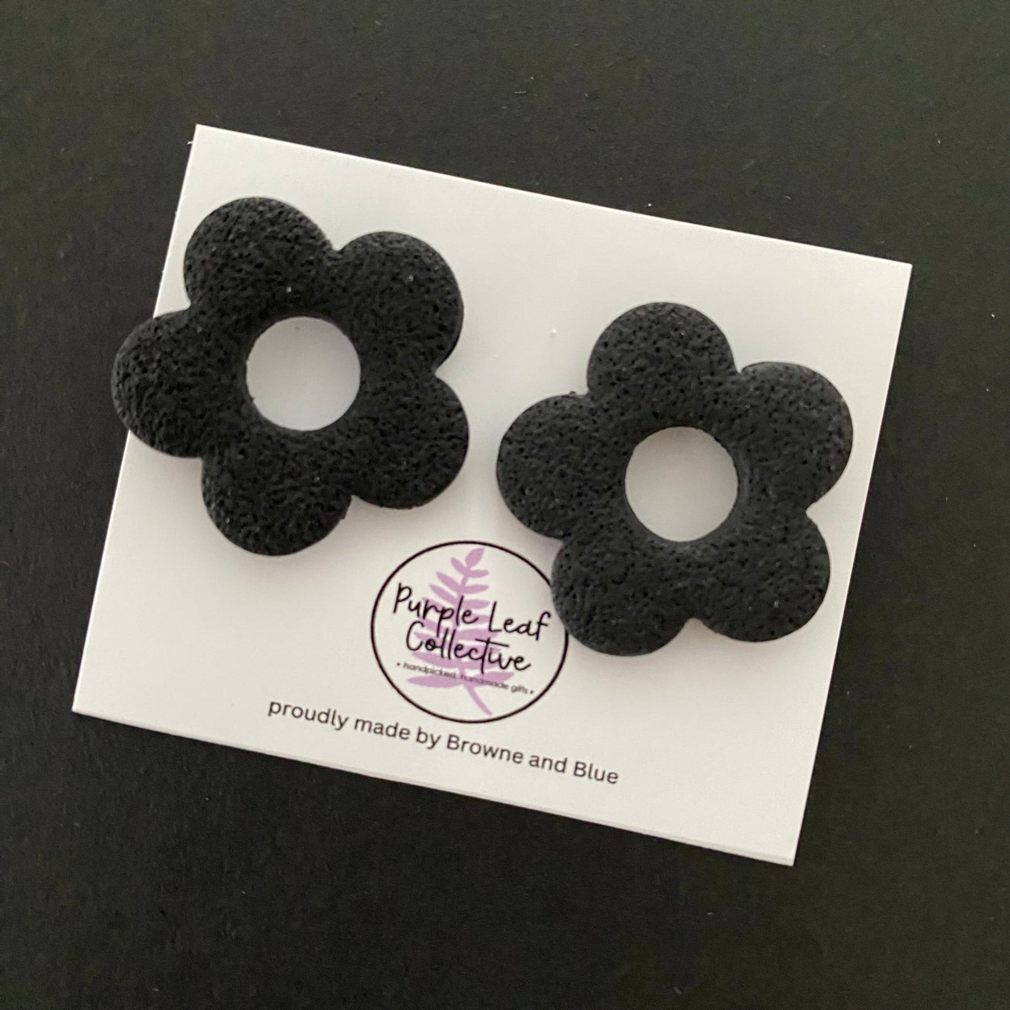 Drop stud earrings with five black polymer clay flower petals, set on surgical steel posts for comfort and durability.