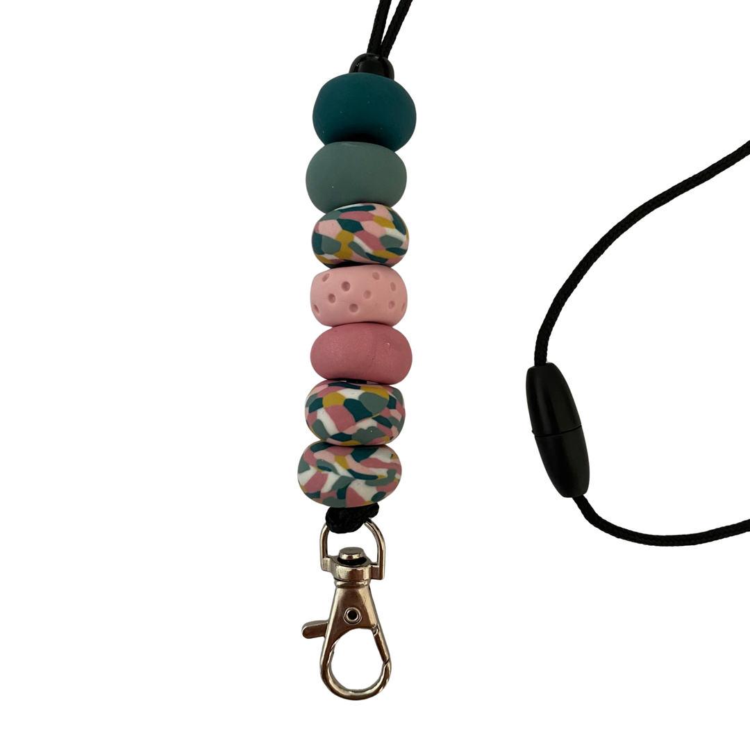 Handmade polymer clay lanyard with seven hand-rolled beads in teals and pinks and vibrant multicoloured beads. Threaded on a nylon cord with a breakaway safety clasp and a silver-plated clip.