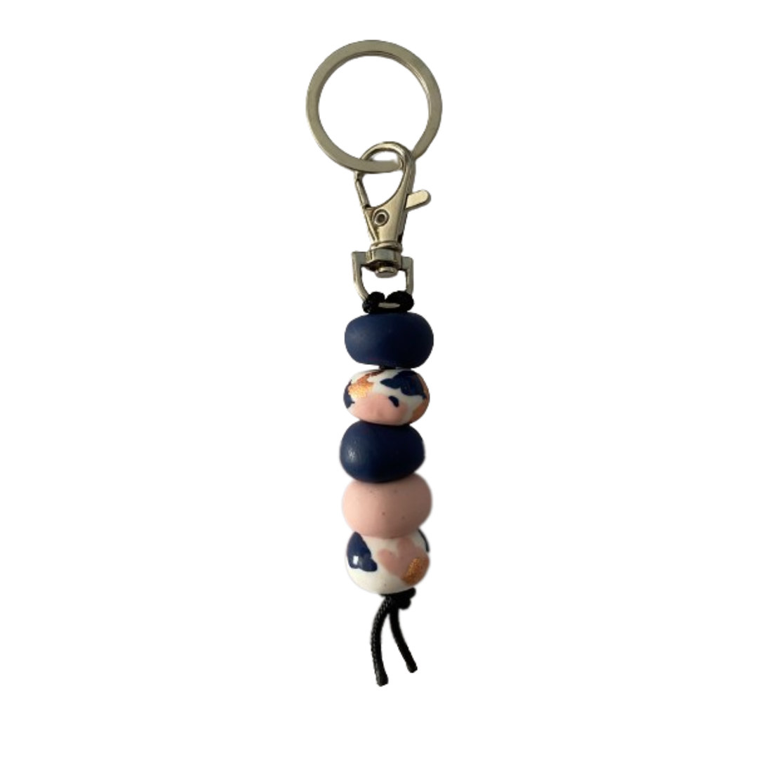 Handmade polymer clay keyring featuring five hand-rolled beads in a mix of navy blue, soft pinks, and intricate patterns with gold foil design, attached to a silver clasp.