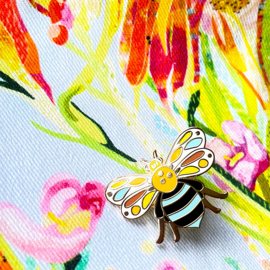 Colourful blue banded bee pin on a floral background.