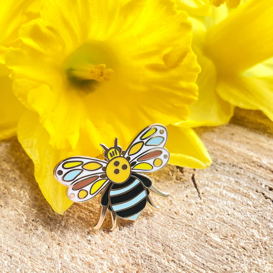 Colourful blue banded bee pin on a yellow flower with wooden surface.
