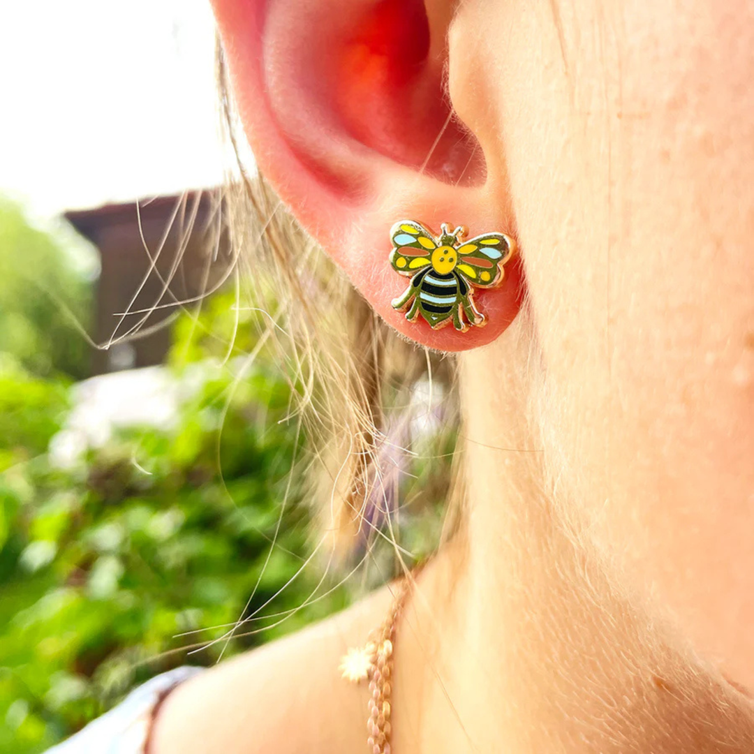 Close-up of an ear wearing a Blue-banded Bee enamel earring.