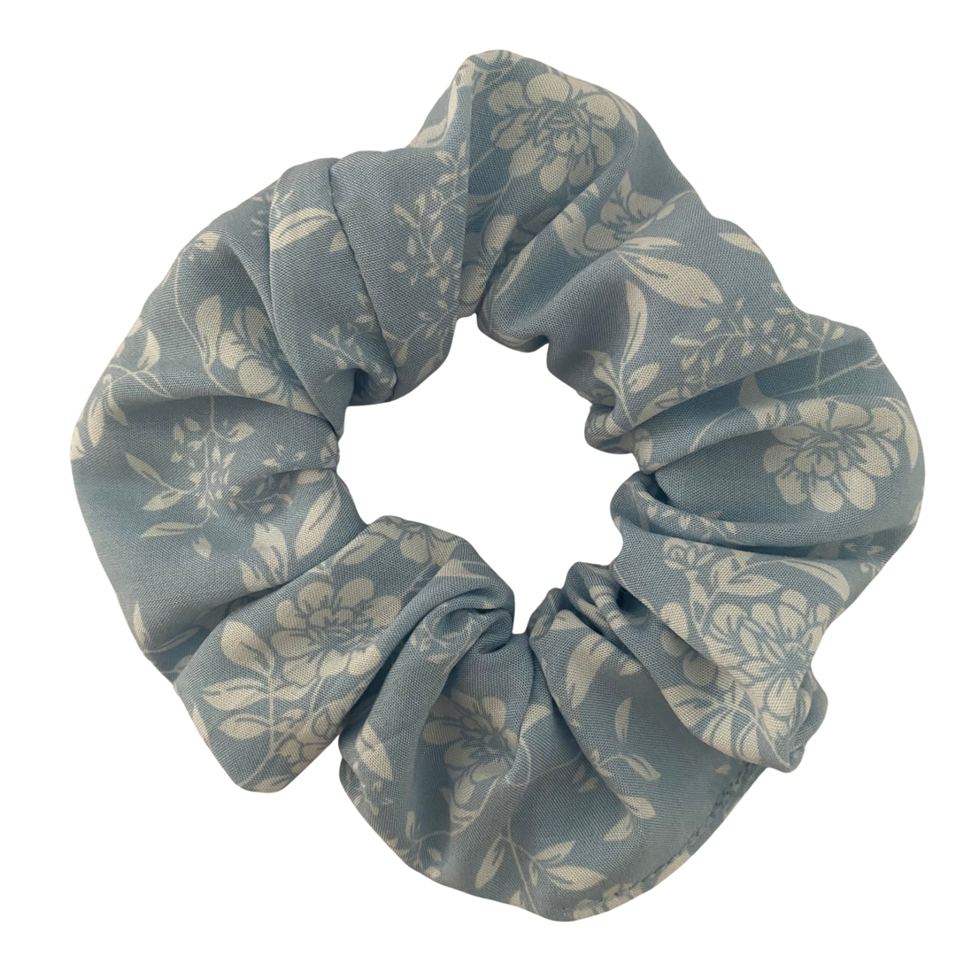 A blue rayon scrunchie featuring an elegant two-toned floral pattern in shades of blue and white.