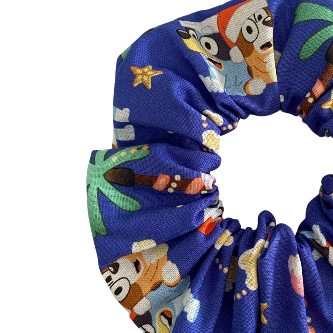 Close up view of Bluey and Bingo wearing Santa hats scrunchie on a dark blue fabric.