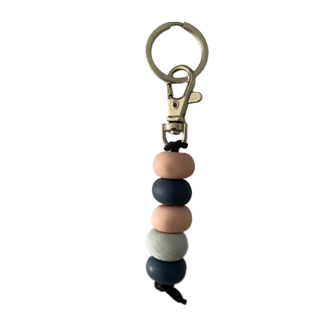 Handmade polymer clay keyring featuring five hand-rolled beads in navy blue and pinks with a marble effect design, attached to a silver clasp.