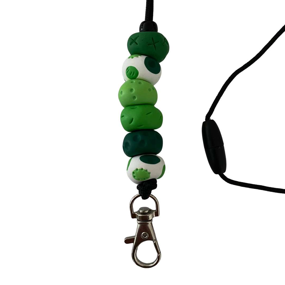 Handmade polymer clay lanyard with six hand-rolled beads in green colours. Threaded on a nylon cord with a breakaway safety clasp and a silver-plated clip.