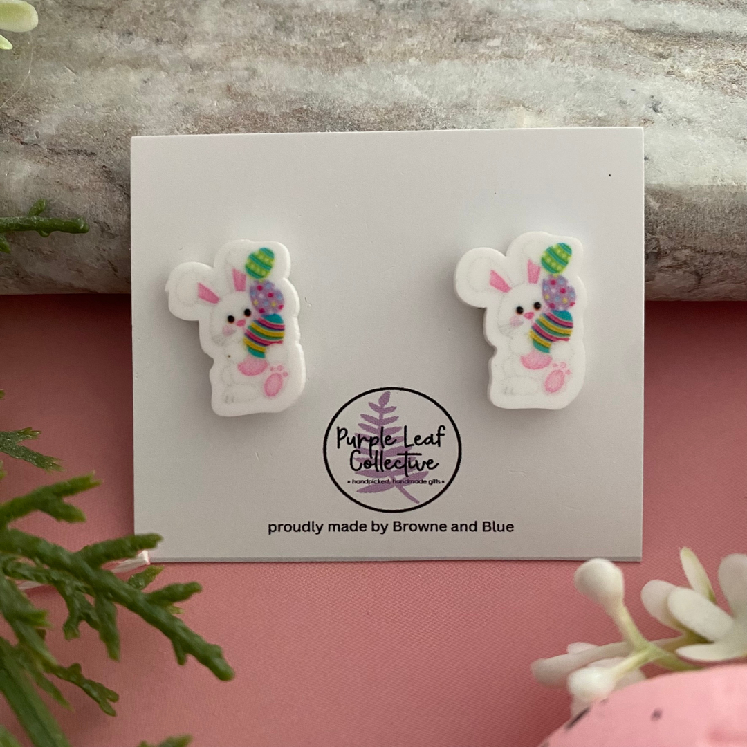 Pair of handmade stud earrings featuring a white bunny balancing three stacked colourful Easter eggs.