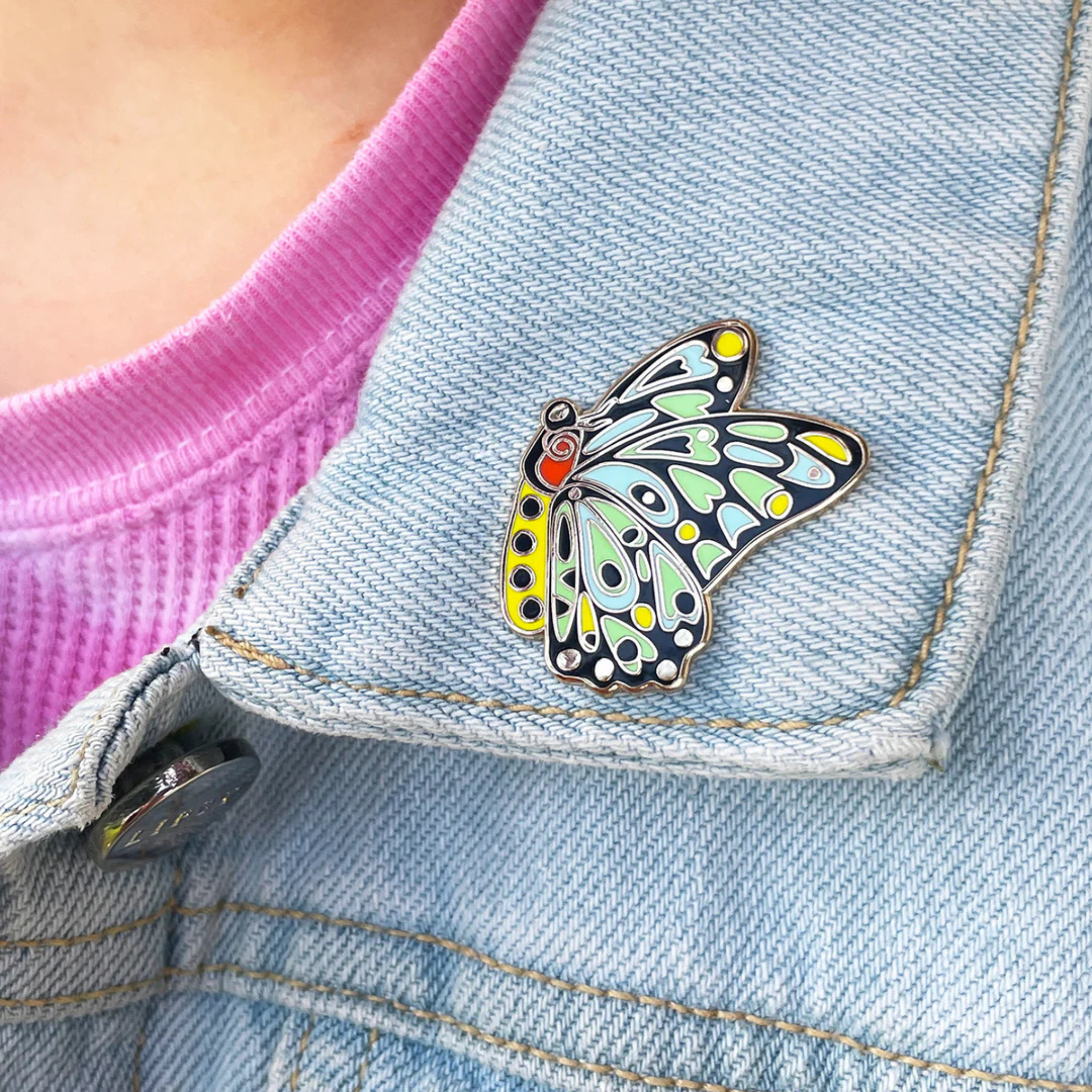 Cairns Birdwing Butterfly enamel pin styled on a denim jacket.