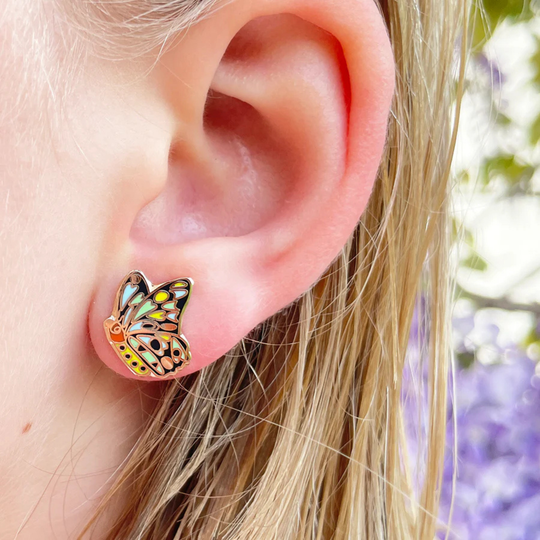 A picture of the Cairns Birdwing Butterly enamel stud earring being worn on the ear lobe.