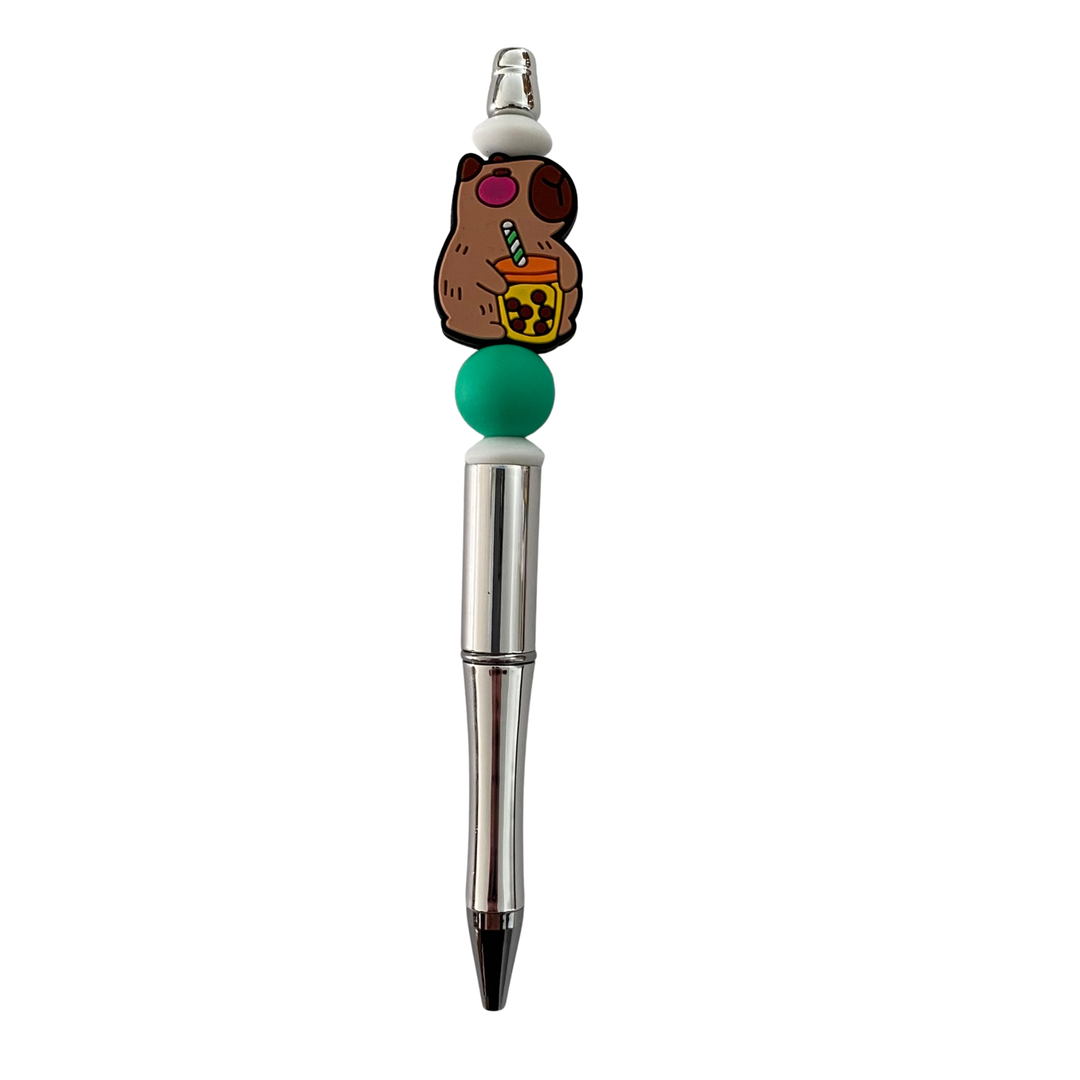 A silver ballpoint pen featuring a Capybara holding a sippy cup and straw.