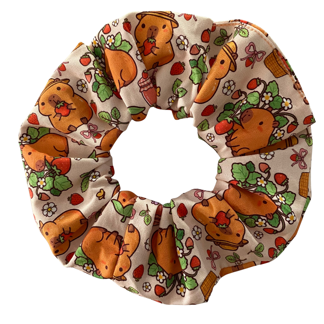 Hair scrunchie featuring a cute cartoon capybara pattern on a apricot fabric.