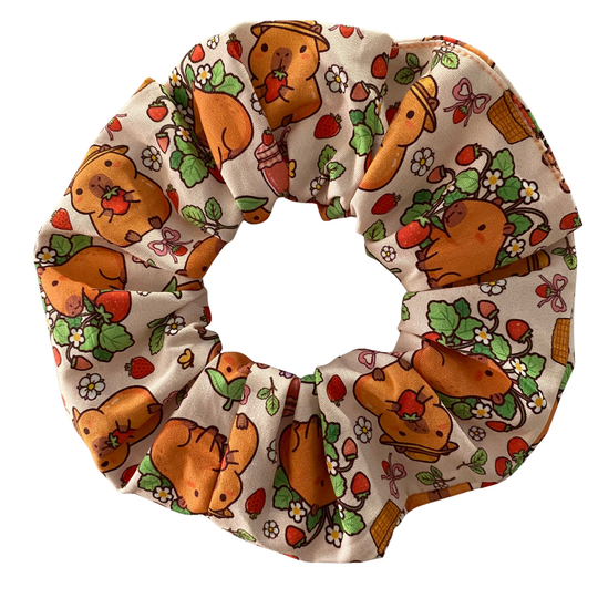 Hair scrunchie featuring a cute cartoon capybara pattern on a apricot fabric.