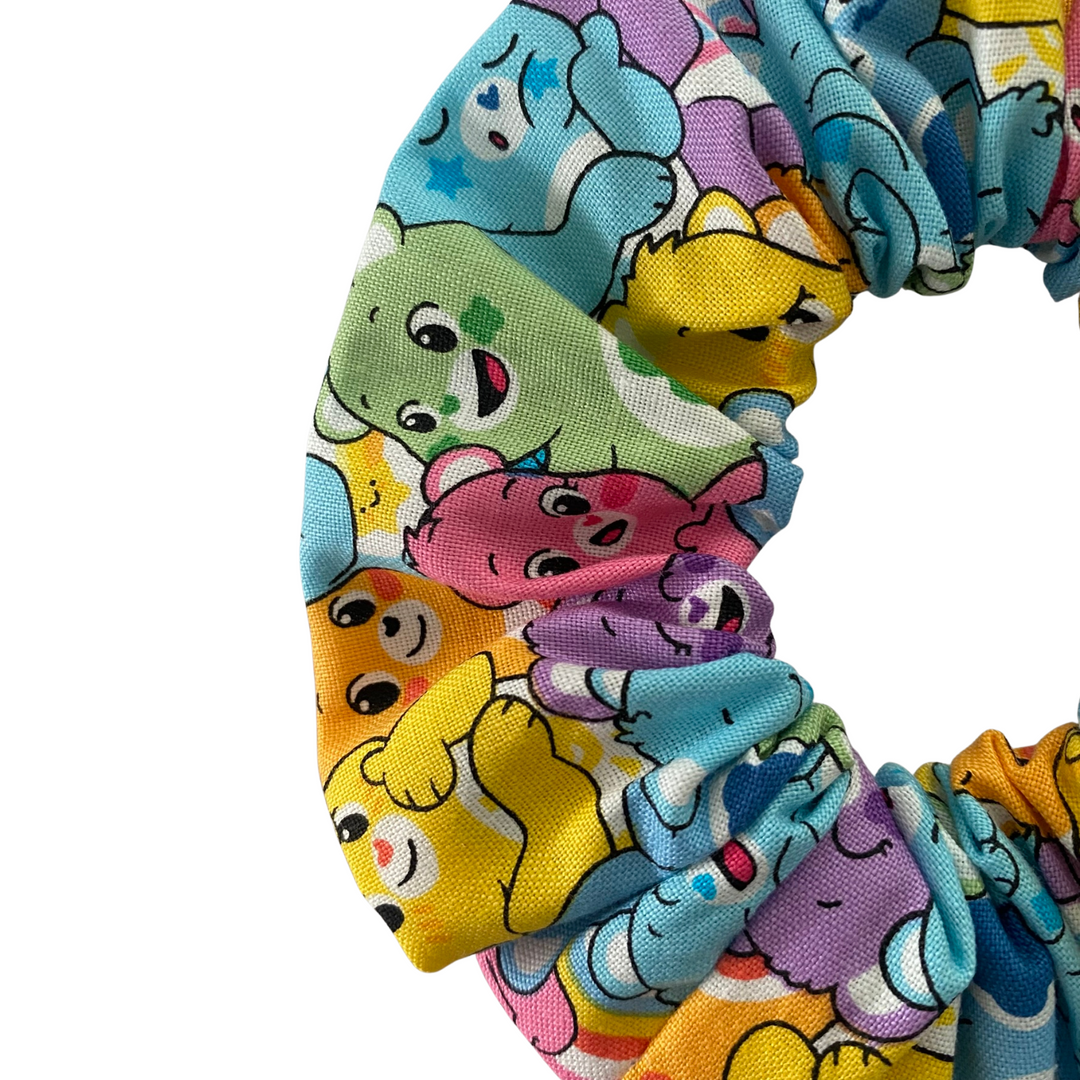 Close up view of colourful scrunchie with Care Bears characters pattern on a white background.