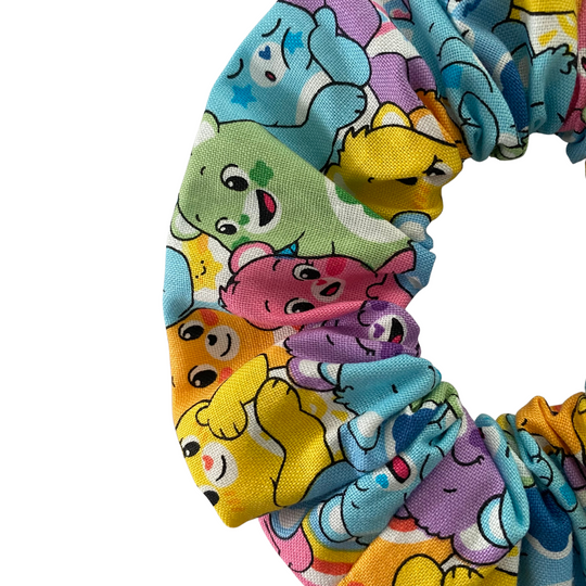 Close up view of colourful scrunchie with Care Bears characters pattern on a white background.