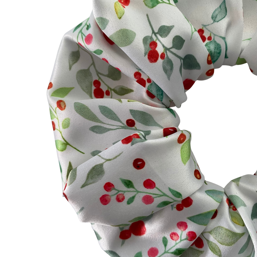 White scrunchie with red berries and green leaves on a white background.