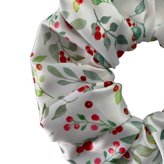 White scrunchie with red berries and green leaves on a white background.