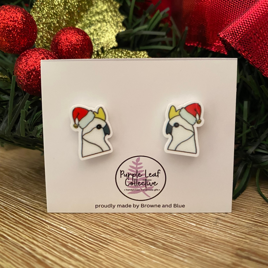 Pair of Christmas cockatoos wearing a red hat on a white card.