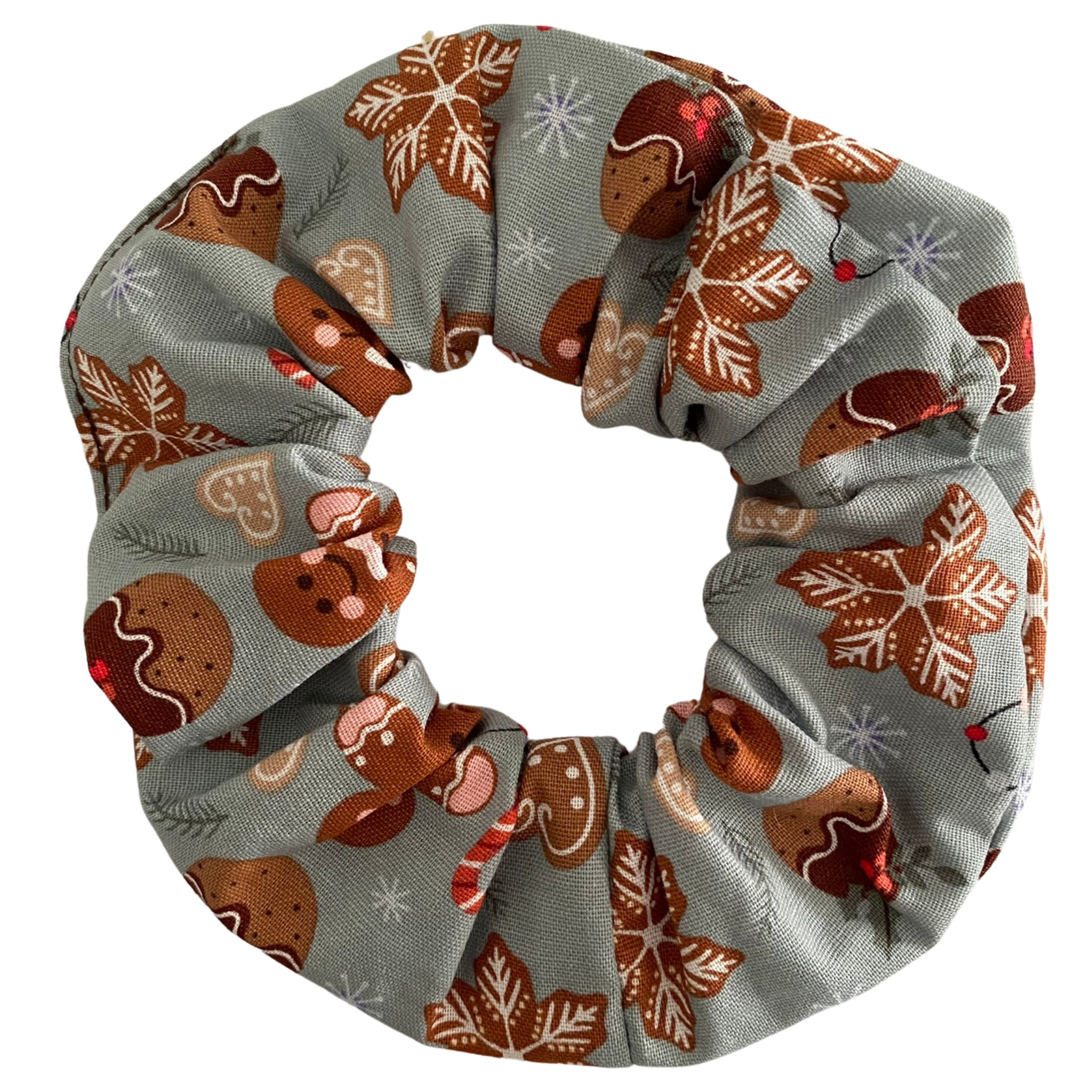 A scrunchie featuring images of gingerbread man and Christmas puddings on a light sliver fabric.