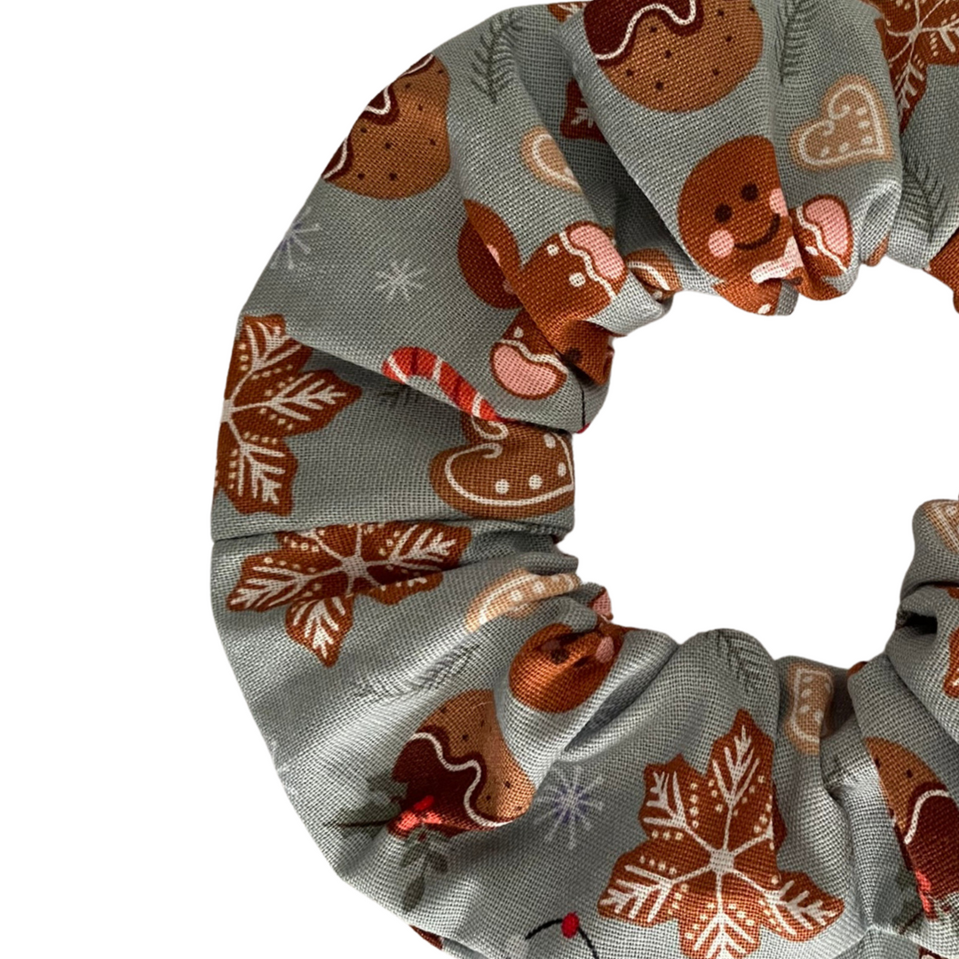 Images of gingerbread man and Christmas puddings on a light sliver fabric scrunchie.