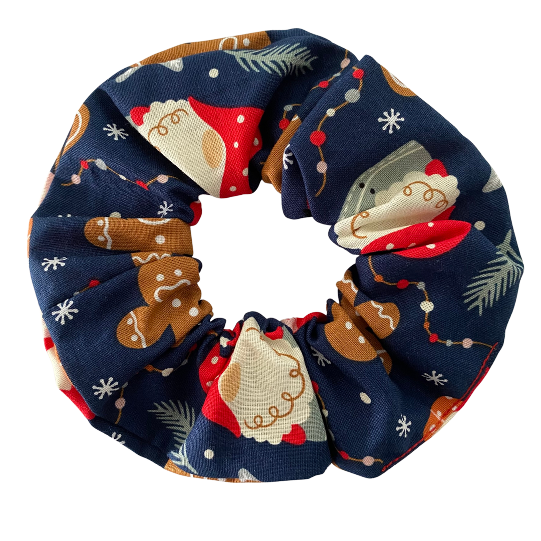 A dark blue scrunchie featuring festive images of gnomes and gingerbread man.
