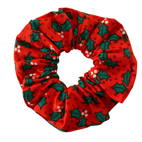 Red scrunchie with green holly leaf pattern on a white background.