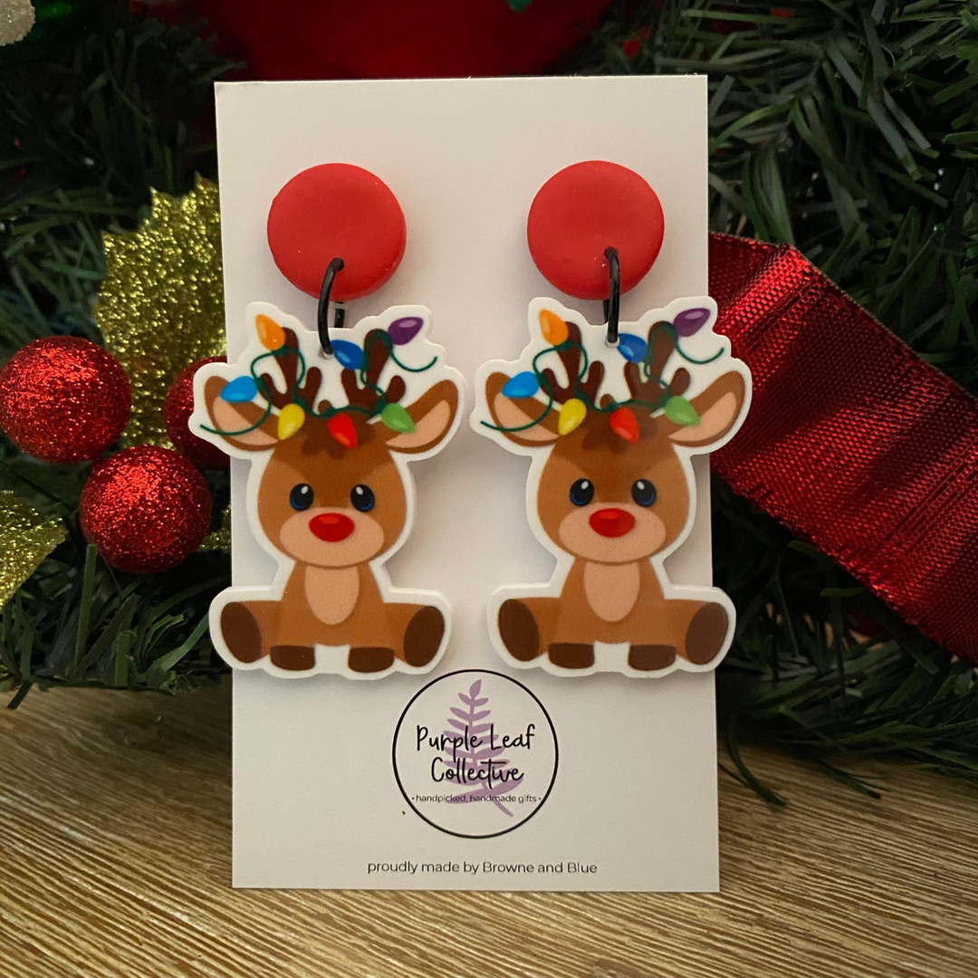 Reindeer wearing Christmas lights earrings with red stud topper on a white card.
